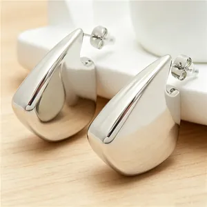 Gros plan de boucles d'oreilles minimalistes irrégulières en acier titane argenté en aileron.
