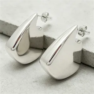 Gros plan de boucles d'oreilles en acier titane en forme d'aileron avec finition miroir.