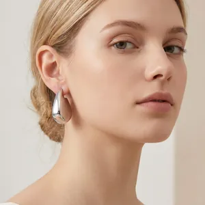 Gros plan d'une boucle d'oreille minimaliste argentée irrégulière sur un mannequin