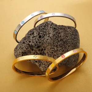 Detailed view of colorful enamel flower stainless steel bangles on volcanic rock prop