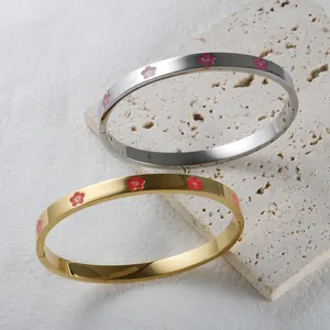 Detail of gold and silver stainless steel bangles with colorful flower patterns.