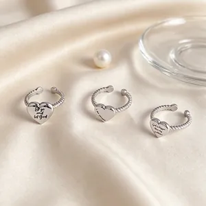 Set of minimalist stainless steel heart rings with engraved inspirational quotes on silk