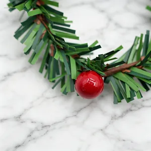 Detailopname van een feestelijke kerstkrans met groene bladeren en rode bes op marmer
