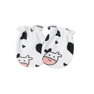 Close-up of soft cotton baby mittens with cute cow print and elastic cuffs