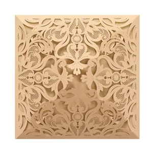 Close-up detail of an intricate laser-cut lace wedding invitation cover in champagne gold