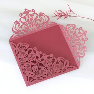 Close-up of elegant burgundy laser-cut lace wedding invitation cover with intricate patterns
