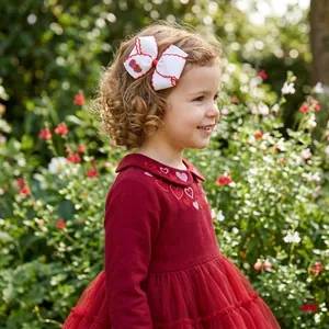 Close-up view of a white heart bow hair clip worn by a little girl in a garden setting