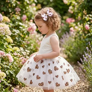 Little girl wearing a handmade leopard heart bow hair clip in a blooming garden.