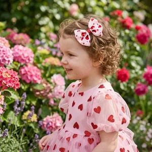 Close-up of a young girl wearing a white and red heart-patterned bow hair clip