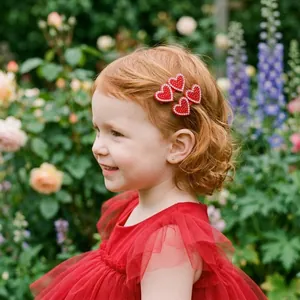 Close-up of a young girl wearing red beaded heart hair clips in a garden setting