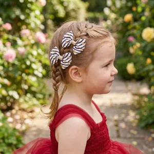 Close-up of a young girl wearing heart patterned bow hair clips in a braided hairstyle.