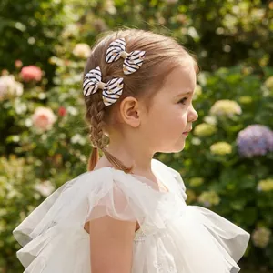 Sweet heart pattern bow hair clips being worn by a little girl in a garden setting.