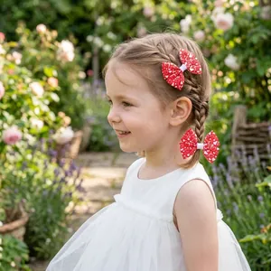 Little girl wearing red heart pattern bow hair clips in a sunny garden setting outdoor detail