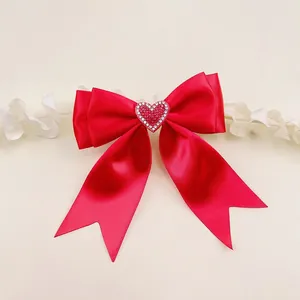 Close-up detail of a handmade red polyester ribbon bow hair clip with rhinestone heart