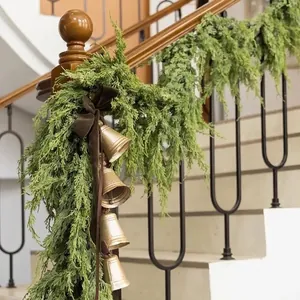 Lush artificial Christmas cedar garland with golden bells for staircase railing decor
