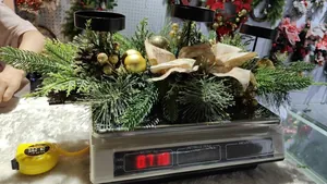 Christmas candle holder with pine branches being weighed on a professional digital scale.