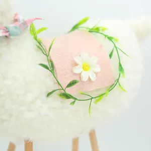 Detail of plush sheep doll featuring pink felt saddle with daisy and green leaves