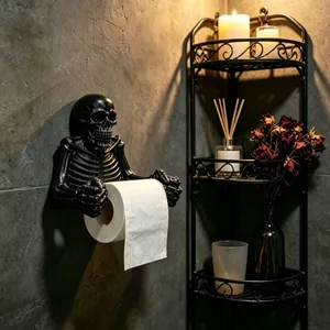 Gothic style black resin skeleton toilet paper holder mounted on a dark stone wall