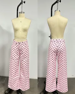 Detailed view of pink and black polka dot high-waisted wide-leg denim trousers.