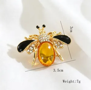 Detailed view of a gold honey bee brooch featuring a yellow resin stone and rhinestones.