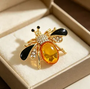 Detailed view of an elegant gold bee brooch with amber gemstone and rhinestones
