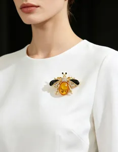 Detailed close-up of an elegant honeybee brooch with rhinestones on a white dress.