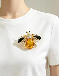 Detailed close-up of an elegant rhinestone honey bee brooch pinned on a white shirt