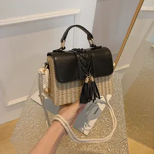 Detailed view of handmade straw woven handbag with black leather flap and tassels