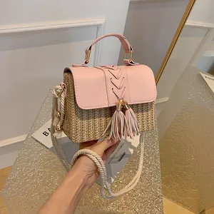 Elegant hand-woven pink straw crossbody bag with stylish tassels and rope strap detail.