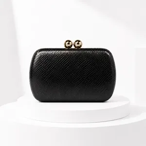Close-up detail of black snake-textured evening clutch bag with gold ball clasp