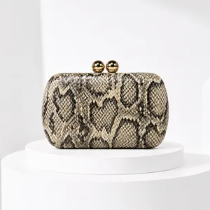 Close-up of snakeskin pattern evening clutch with elegant gold spherical clasps.