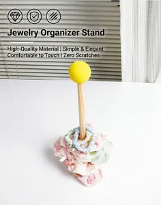 Detalle de un soporte organizador de gomas de pelo en madera con bola decorativa amarilla