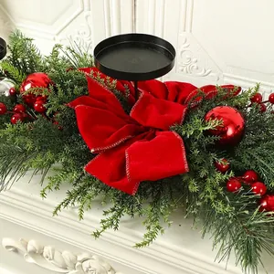 Close-up detail of Christmas garland with red velvet bow and black candle holder base.