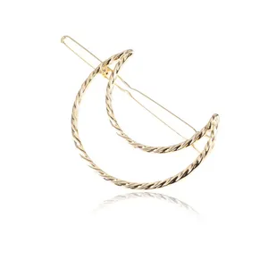 Detail view of a gold twisted moon-shaped hair clip with intricate braided texture.
