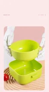 Green plastic bowl for baby food container set shown held by hands in macro detail