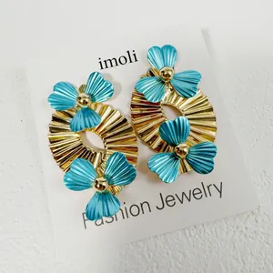 Détail de boucles d'oreilles vintage en feuilles dorées avec accents de fleurs bleues