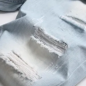 Detailed close-up of light blue ripped denim shorts for men featuring distressed fraying