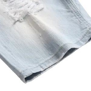 Close-up of men's ripped light blue denim shorts with distressed detail and raw hem.