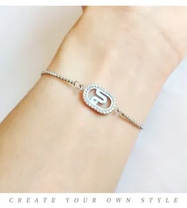 Close-up of silver-toned adjustable bracelet with a crystal-paved oval charm.