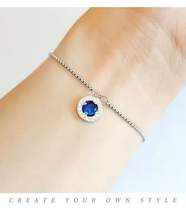 Macro detail of adjustable box chain bracelet featuring a blue stone pendant on wrist