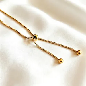Adjustable 18K gold plated box chain tennis bracelet with slider clasp on white silk background