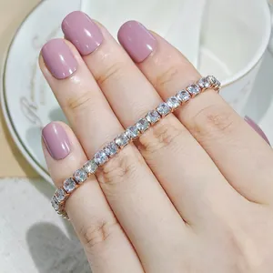 Detailed view of a sparkling zircon tennis bracelet worn on a hand with pink nails