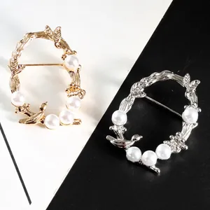 Broches en perles de vigne en or et argent sur fond bicolore noir et blanc.