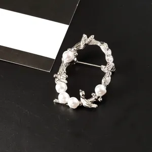 Élégante broche en forme de feuille et de vigne argentée avec perles blanches sur fond sombre