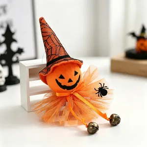Detail of a plush Halloween pumpkin witch decoration featuring orange gauze and bells
