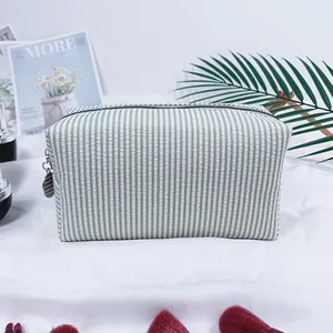 Detailed macro shot of a green and white striped seersucker makeup bag with a zipper.