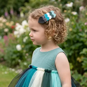 Detail view of a young girl wearing a colorful glitter heart hair clip in a lush garden