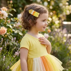 Close-up detail of a colorful rainbow glitter heart hair clip on a girl in a garden