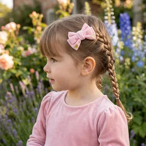 Close-up of a young girl wearing a pink velvet bow hair clip with gold glitter hearts.