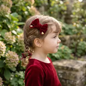 Detailed view of handmade red velvet bow hair clip with gold glitter hearts on girl